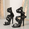 Pair of black open toe buckle strap heels in three-quarter view