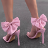 Pink ankle strap stiletto sandals worn from rear with bows visible